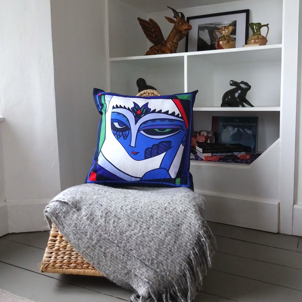 fiona the fierce brightly coloured face in blues, red, purple, green and white. Sitting on rocking chair. wicked imp designs