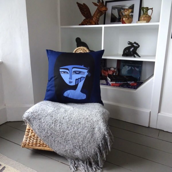 Madam X cushion. Large face with blues and black hair in situ on rocking chair. wicked imp designs